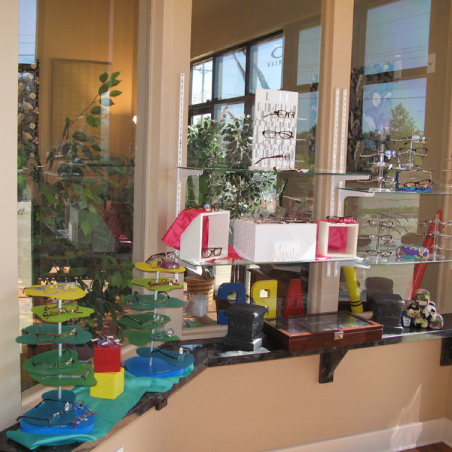 Display shelf with colorful eyewear stands and accessories near a window, bright and playful mood